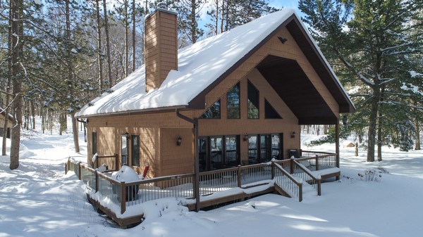 Snow covered wood cabin with surrounding deck