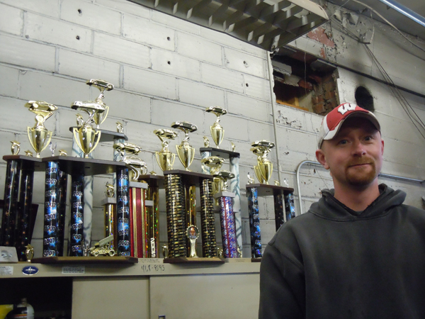 Mark Helene standing next to many tall trophies