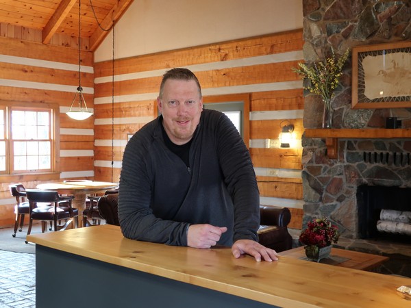 Century 21 agent Jason Lee inside cabin with fireplace