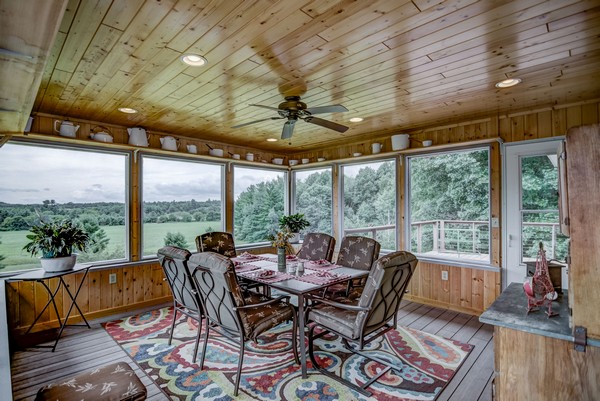 Screened in porch with ceiling fan and dining area with rug