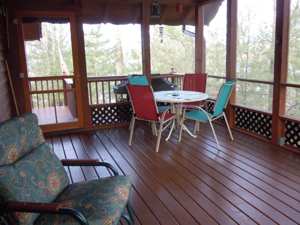 Screened in porch with small table and chairs and wood floors