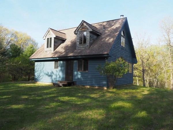 Small blue cabin with brown peaked roof on Clam River