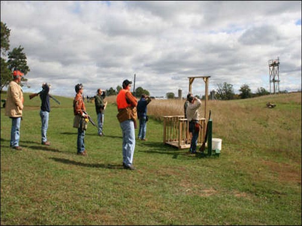 Men standing in a field with guns practicing shooting