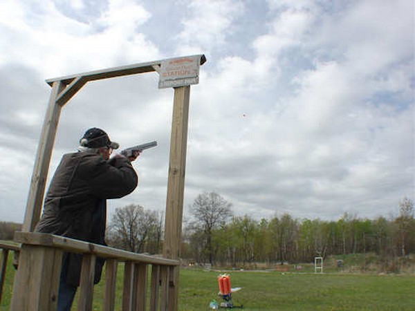 Man in wood stand with his gun pointed to the sky