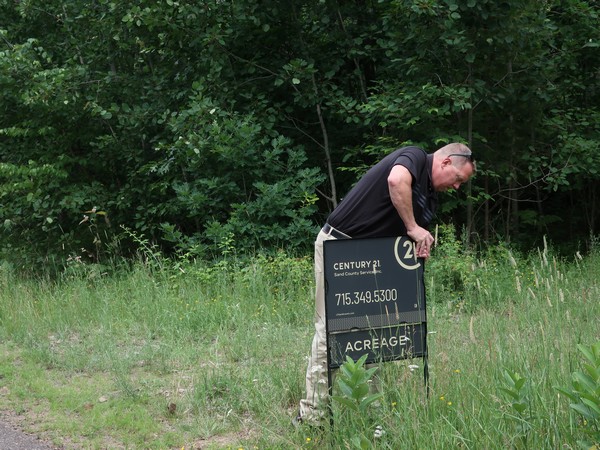 Century 21 agent sticking listing sign in yard of property