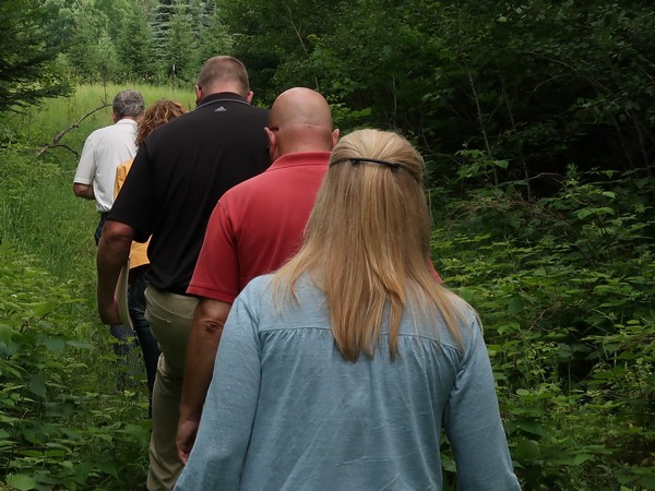 Century 21 agents walking through the forest of a property