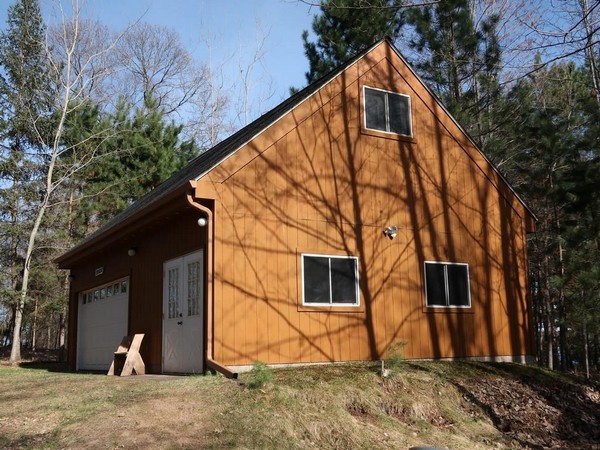 Tall wooden garage with peaked roof on hill