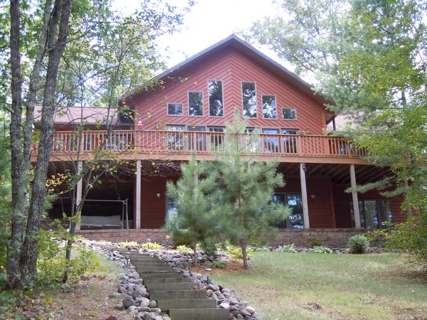 Red wood cabin with balcony along perimeter of second floor